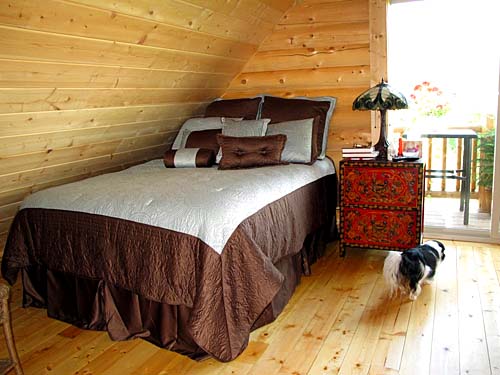 Cozy attic bedroom with wooden walls and a small bedside table