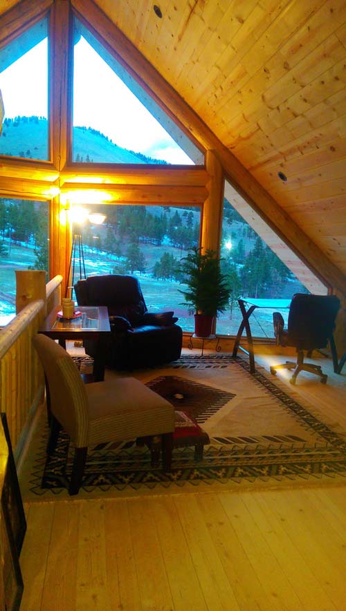A cozy attic loft with armchairs and a scenic mountain view