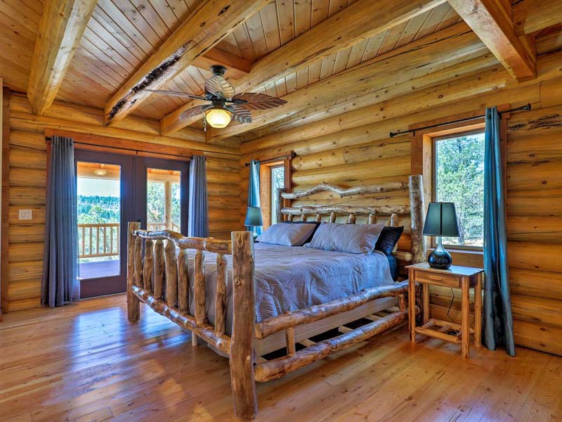 Rustic log cabin bedroom with wooden furniture and forest view