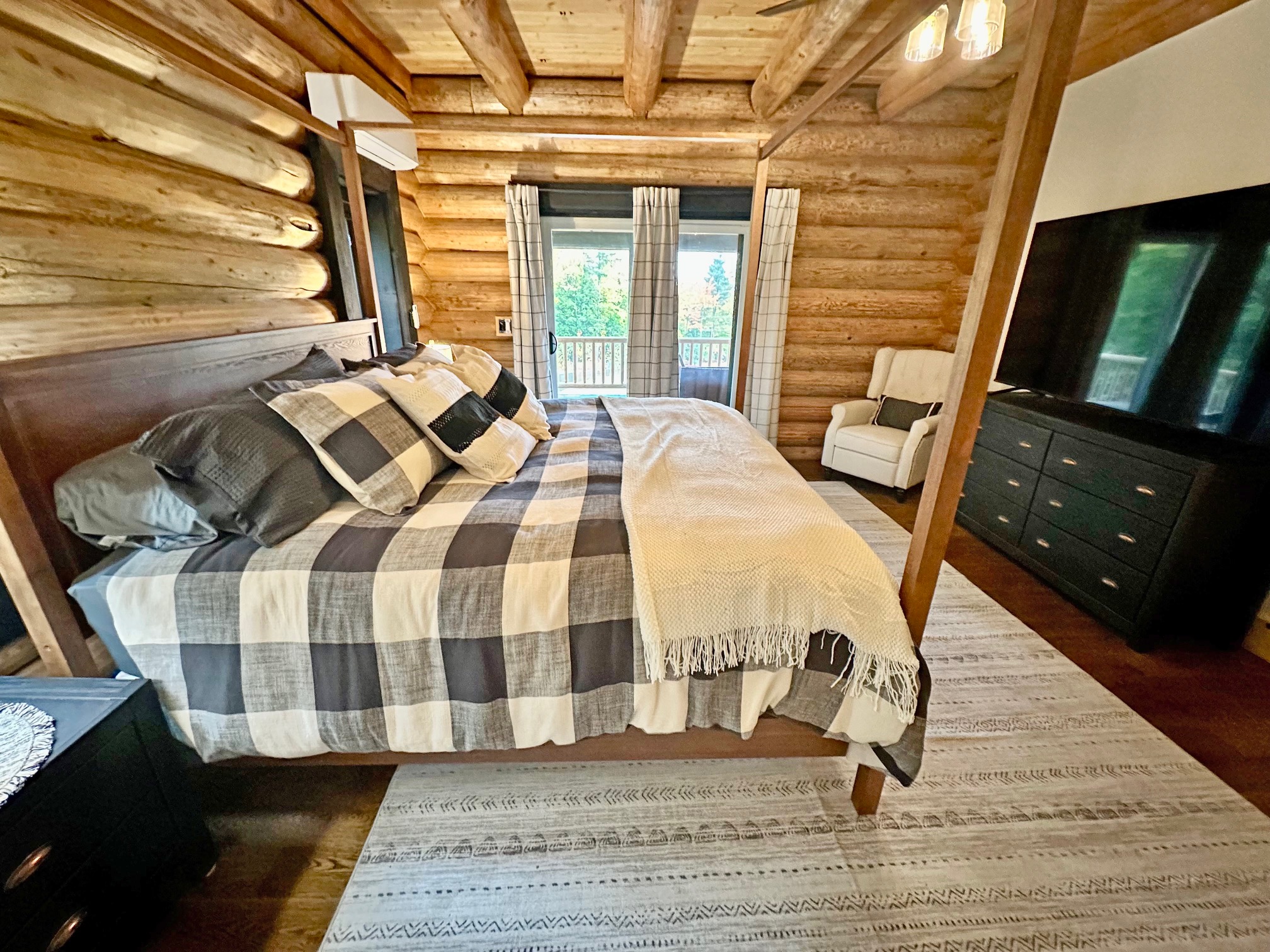 Cozy log cabin bedroom with plaid bedding and large window