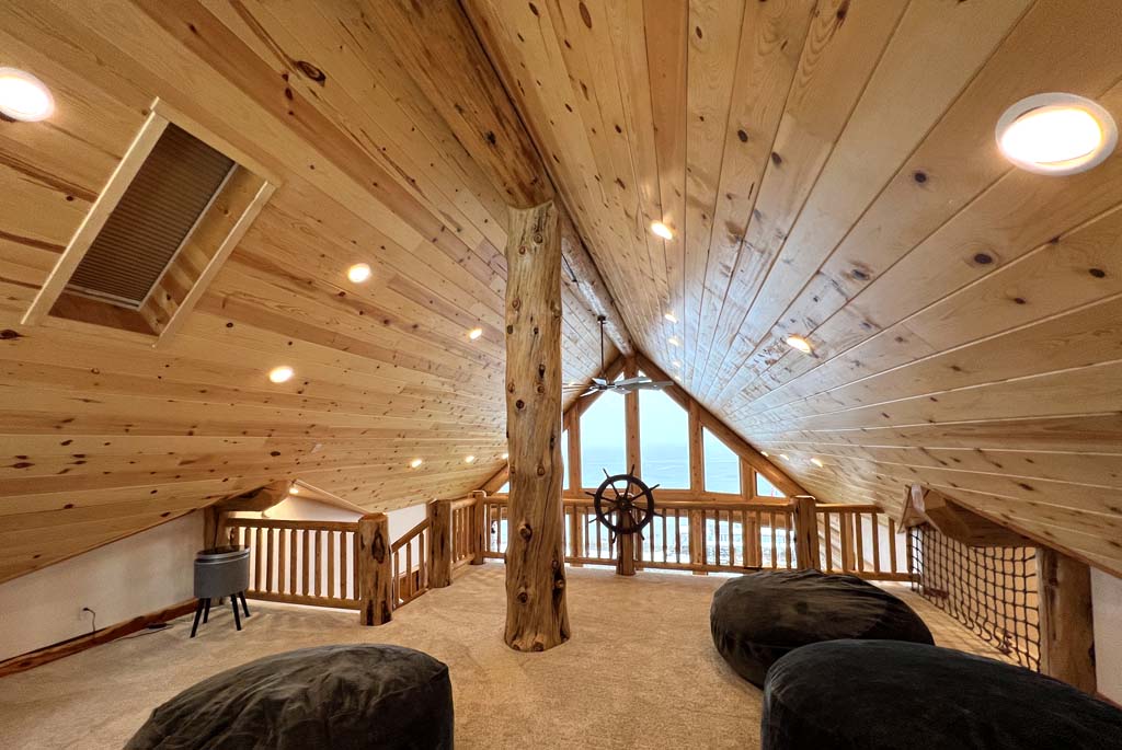 Rustic wooden attic room with cozy seating and large window