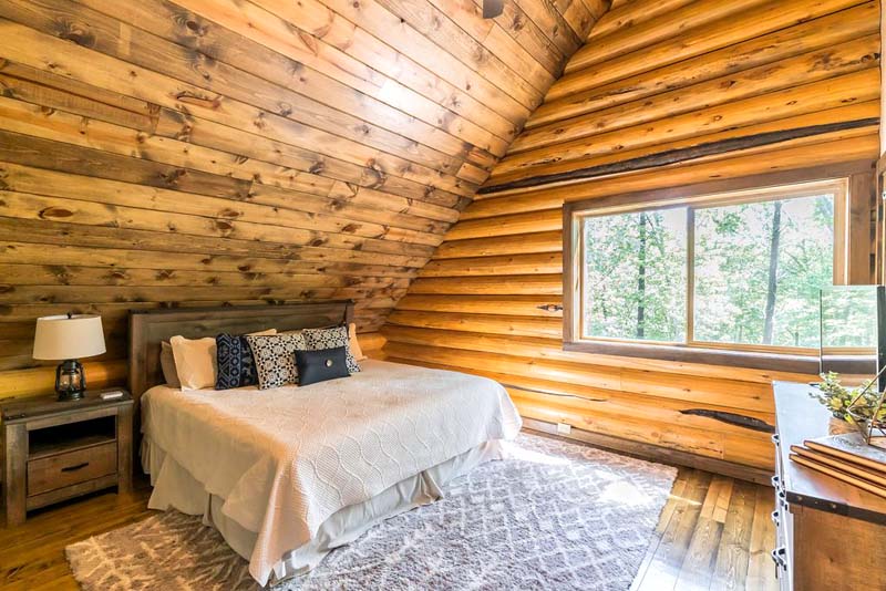 Rustic wooden cabin bedroom interior with cozy bed and window