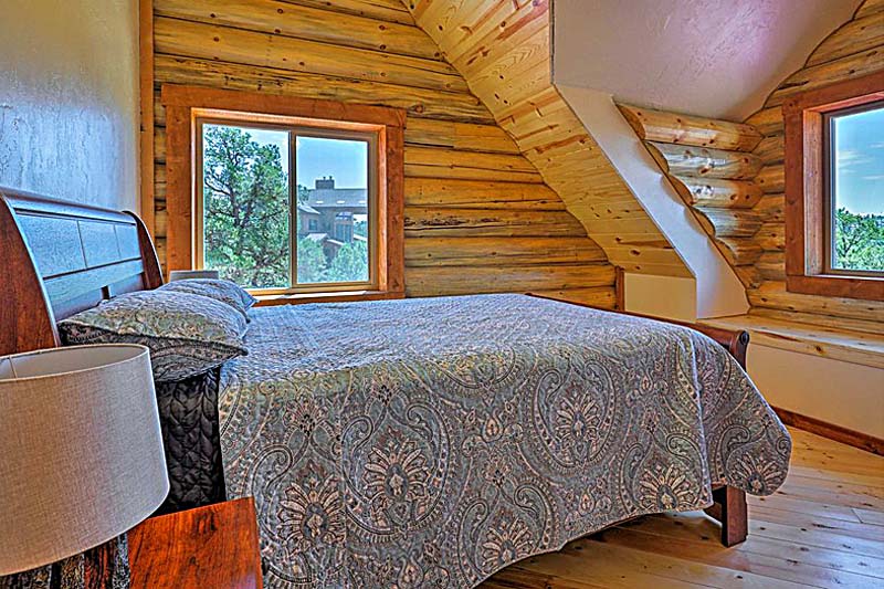 Cozy rustic bedroom with wooden walls and scenic window view