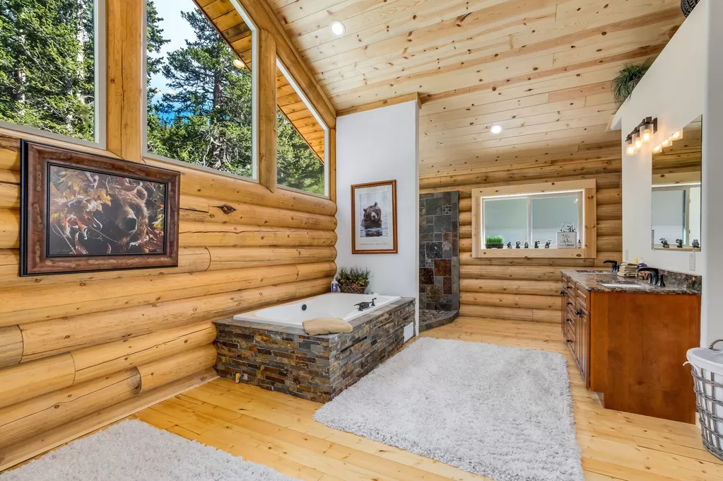 Rustic log cabin bathroom with large windows and wood accents