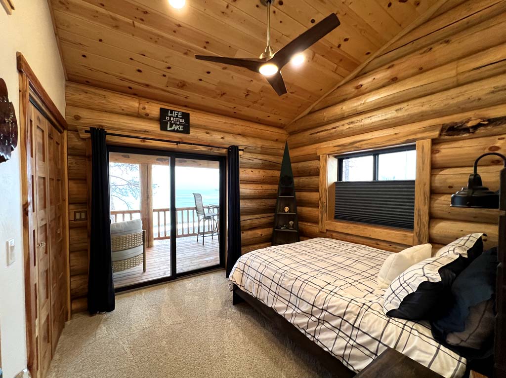 Cozy log cabin bedroom with wooden walls and large window view