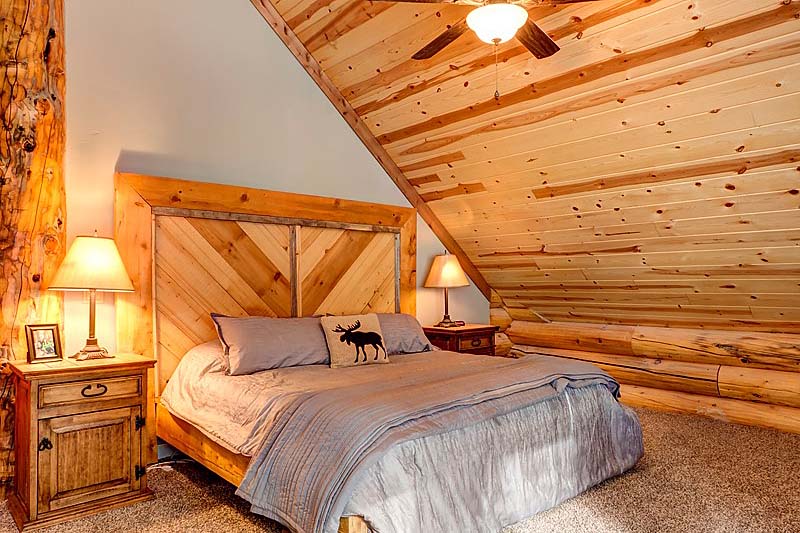 Cozy rustic bedroom with wooden bed and sloped ceiling