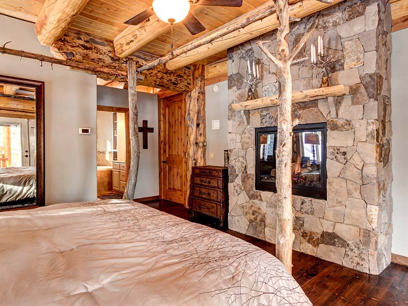 Rustic bedroom with stone fireplace and wooden ceiling beams