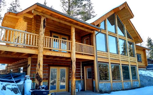 Wooden cabin with large windows in a snowy forest setting