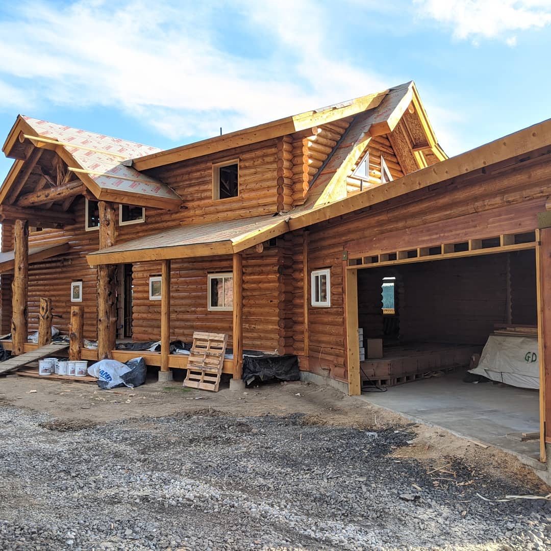 Log cabin under construction with wooden beams and garage