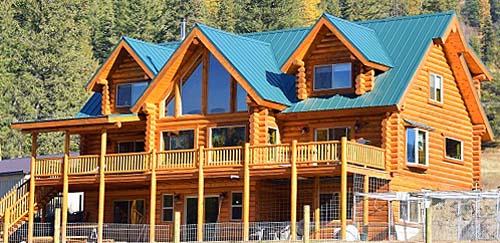 Wooden cabin in a forest setting with blue roof and large windows