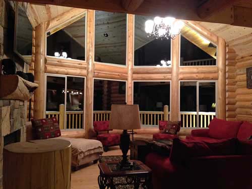Cozy log cabin living room with large windows and red seating