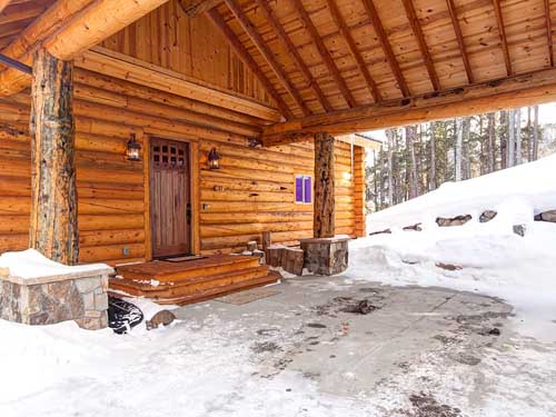 Cozy snowy log cabin entrance with wooden beams in winter forest