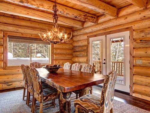 Rustic log cabin dining room with antler chandelier lighting