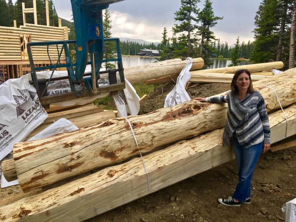 Woman standing beside large wooden logs at construction site