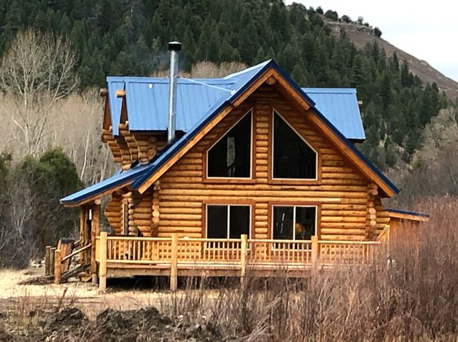 Wooden cabin in forested mountain landscape with blue roof
